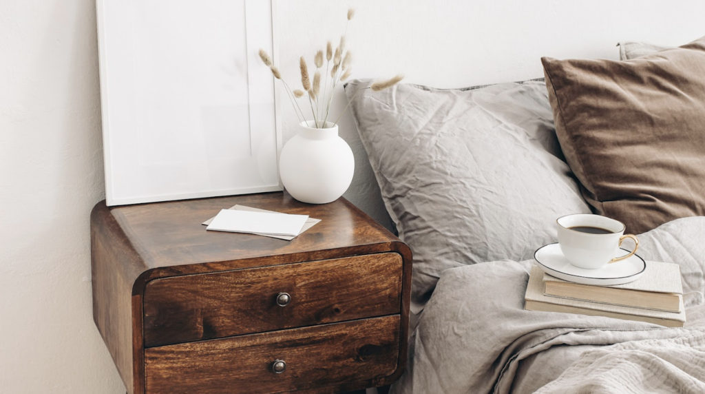 A wooden nightstand next to a bed